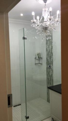 uma casa de banho com um chuveiro em vidro e um lustre. em 513 on Mulberry em Pretoria