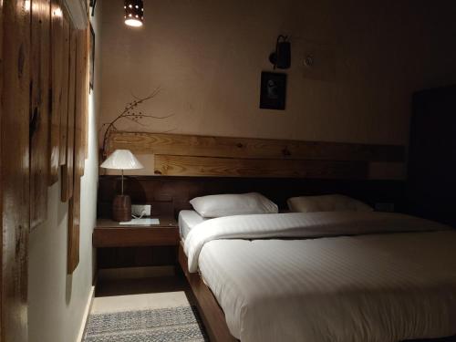 a bedroom with two beds and a table with a lamp at Jaadooghar Maatre Yoga Retreat in Marchula