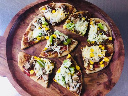 a wooden plate with four slices of pizza on it at Jaadooghar Maatre Yoga Retreat in Marchula