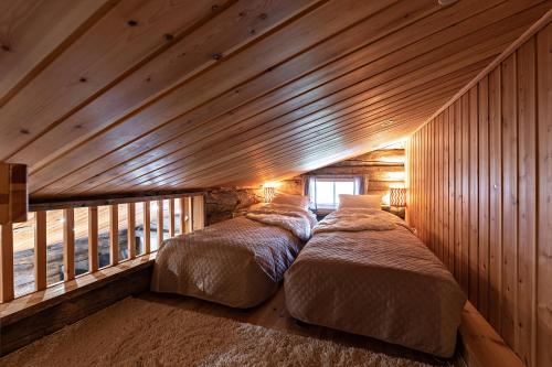 two beds in a room with wooden walls at UnelmaPirkelo in Ruka