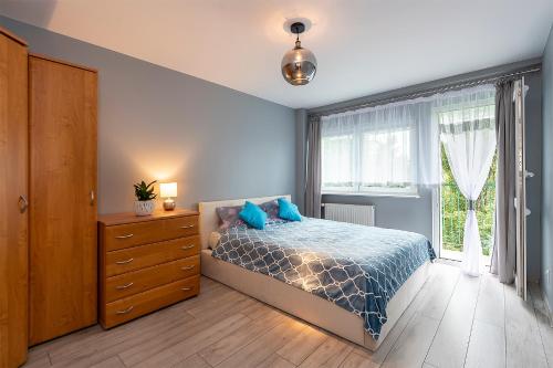 sypialnia z łóżkiem, komodą i oknem w obiekcie Apartament LILA w Łodzi