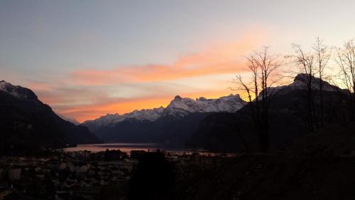 a sunset over the mountains with a city and a lake at Ferienwohnung Seesicht in Brunnen