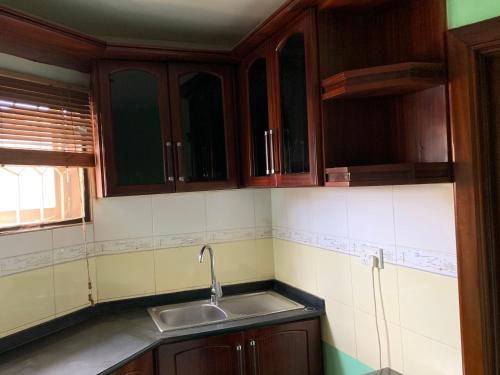 a kitchen with wooden cabinets and a sink at Suus Rahma Guest House & Apartments in Accra