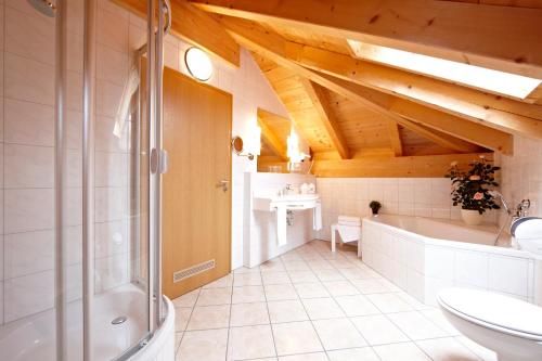 y baño con ducha, lavabo y bañera. en Hotel Schatten, en Garmisch-Partenkirchen