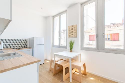 - une cuisine blanche avec une table et quelques fenêtres dans l'établissement Le Cosy Blancarde -Appartement 1 chambre 4 pers- Clim Parking, à Marseille