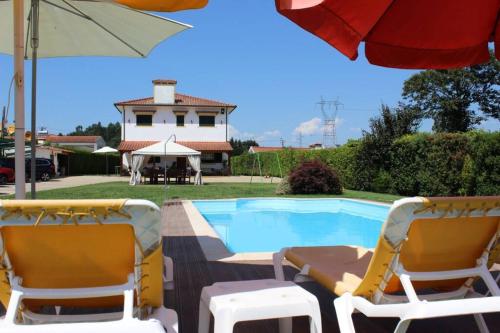two chairs and an umbrella next to a swimming pool at CORVITINHO in Guimarães