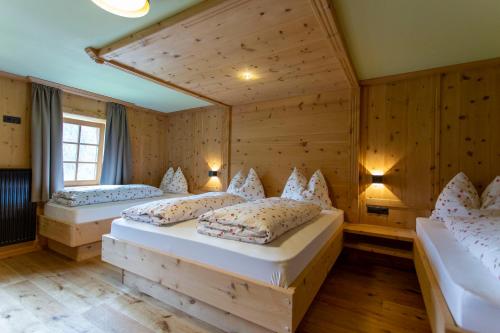 two beds in a room with wooden walls at Hanslerhof in Braies