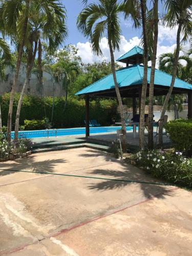 a pavilion with a blue roof next to palm trees at La Gaviota B1 in Juan Dolio