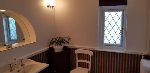 a bathroom with a sink and a window and a chair at Wychwood House in Tenby
