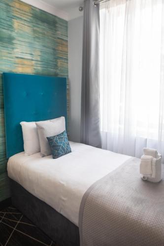 a bedroom with a large bed with a blue headboard at Paddington Park Hotel in London