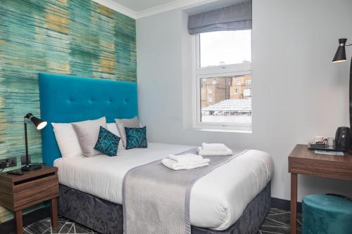 Paddington Park Hotel في لندن: غرفة نوم مع سرير مع اللوح الأمامي الأزرق