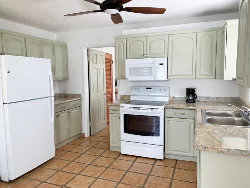 a kitchen with white appliances and a ceiling fan at Sand Castle on the Beach - Adults Only in Frederiksted