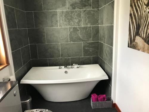 a white bath tub in a bathroom with a tile wall at Strathspey in Kyleakin
