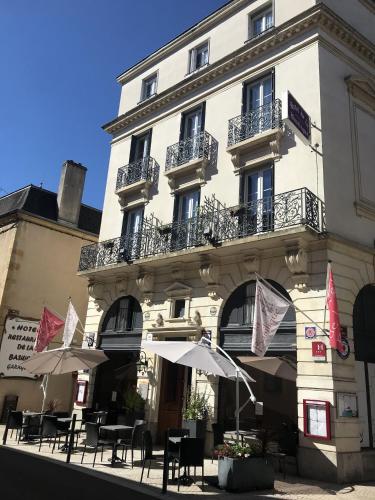 a building with tables and umbrellas in front of it at Hotel de la Basilique in Paray-le-Monial