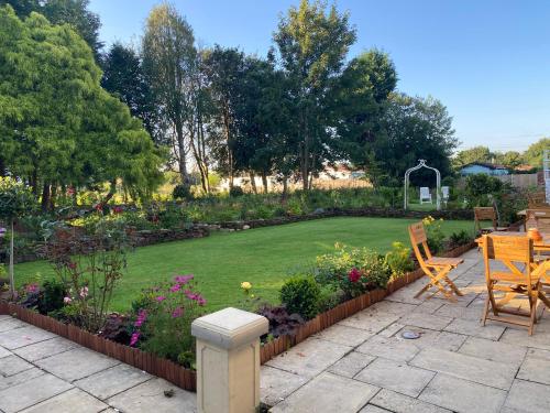 a garden with a lawn and chairs and flowers at Stone House Hotel ‘A Bespoke Hotel’ in Stone