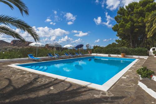 una piscina con sedie e ombrelloni in un cortile di Le Dimore della Villa dei Sogni a Vulcano