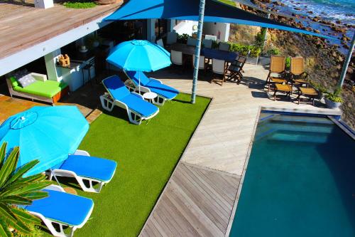 a group of chairs and umbrellas next to a swimming pool at 185 on BEACH Boutique Suites in Gordonʼs Bay