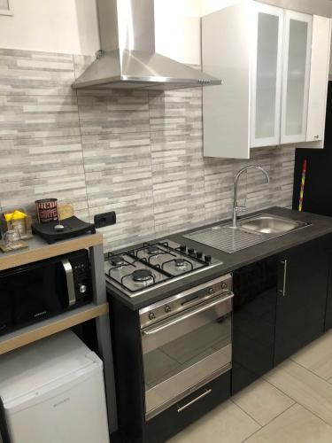 a kitchen with a stove and a sink and a microwave at Maison Jean-Luc - app Vittorio in Bra