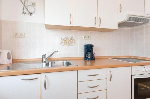 a kitchen with white cabinets and a sink at Studio Point of view in Punat