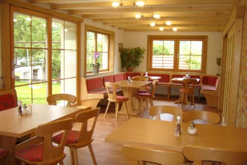 a restaurant with wooden tables and chairs and windows at Gästehaus Schlegel in Gunzesried