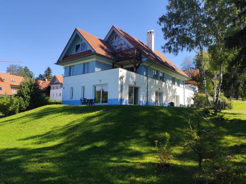 uma grande casa branca com um telhado vermelho em Lipno Riviéra - Myši v botě em Lipno nad Vltavou