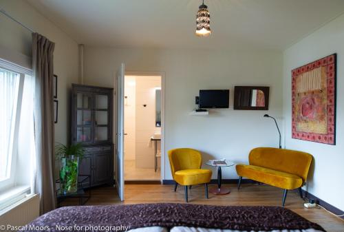 a living room with two chairs and a table at De Auw Sjoekelaatfabriek in Gulpen