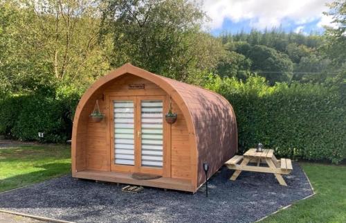 a wooden shed with a picnic table in a yard at Torrent Walk Glamping Huts in the Heart of Snowdonia in Dolgellau
