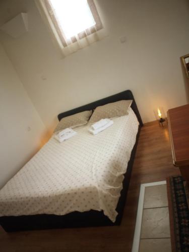 a bedroom with a bed with white sheets and a window at Apartman Milica in Kremna