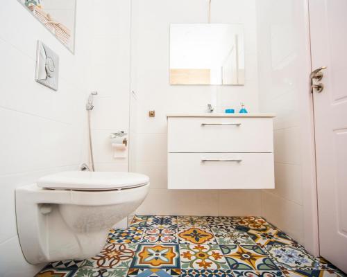 a bathroom with a toilet and a tile floor at Villa Ina & Eva Bayview Deluxe in Burgas City