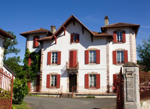 uma grande casa branca com persianas vermelhas em Maison Graciateguy em Saint-Étienne-de-Baïgorry