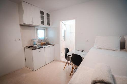 Habitación blanca pequeña con cama y cocina en Esmeralda Apartments, en Apollonia