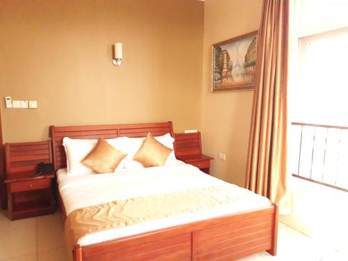 a bedroom with a bed with white sheets and a window at Chelsea Hotel in Dar es Salaam