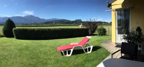 a red chair sitting on the grass next to a house at Appartements Panorama Schlössl in Velden am Wörthersee
