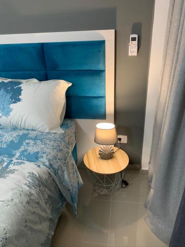 a bed with a blue headboard and a table with a lamp at Sea&Center Lux in Bar