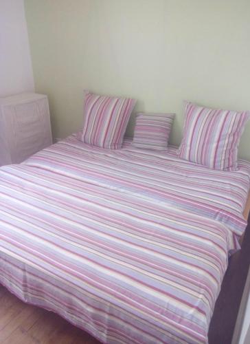 Elle comprend un grand lit avec des draps et des oreillers rayés. dans l'établissement Plage et centre, à Villers-sur-Mer