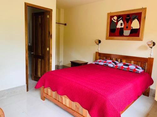 a bedroom with a bed with a red bedspread at La Casa de Cecilia Mindo in Mindo