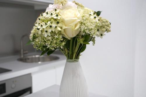 a white vase filled with white flowers on a counter at Noemiz Exclusive Apartments in Budapest