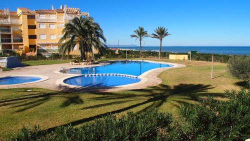 una piscina con palmeras, un edificio y el océano en Marina Azul ElConserje, en Denia