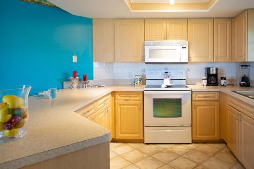 a kitchen with yellow cabinets and a white stove top oven at 505 - Gulf Strand in St. Pete Beach