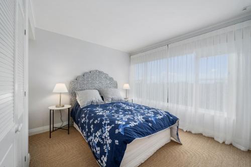 um quarto com uma cama com uma colcha azul e branca em Nga Karoro - Raumati Beach Holiday Home em Raumati Beach