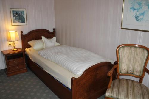 a bed in a room with a chair and a lamp at Appartementhaus Wimmerhof in Bad Füssing