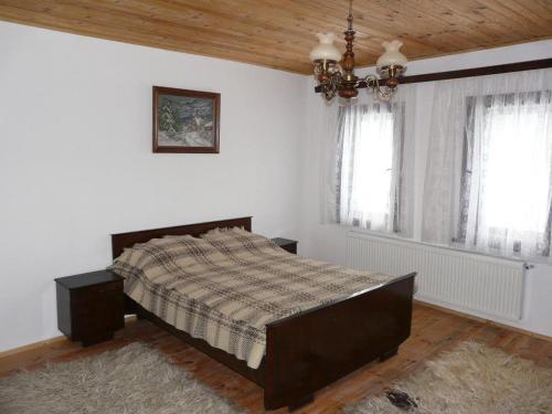 a bedroom with a large bed and two windows at Staroto Shkolo House - rooms for guests in Bozhentsi