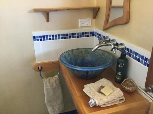 a bathroom with a blue bowl sink on a wooden counter at Forest Walks Lodge in Jackeys Marsh