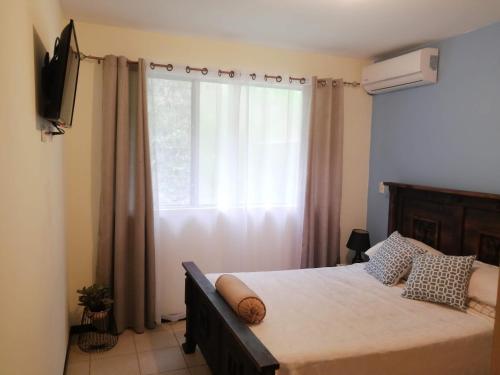 1 dormitorio con 1 cama, ventana y TV en Casa playa herradura #1, en Herradura