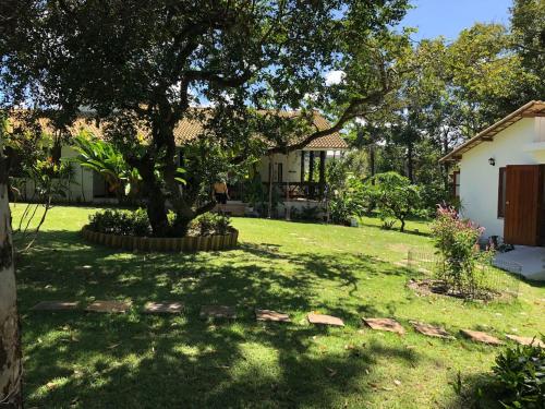 a yard with a tree and a house at Casa paradise perto da praia Guarajuba - BA in Camacari