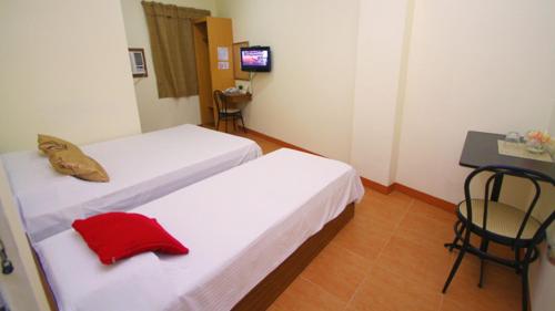 a room with two beds with a red pillow on them at Robe's Pension House in Cebu City