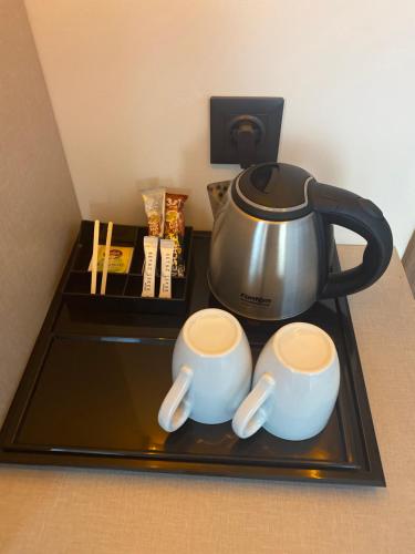a tea kettle and two cups on a tray at OFURO WORLD HOTEL SPA in Izmir