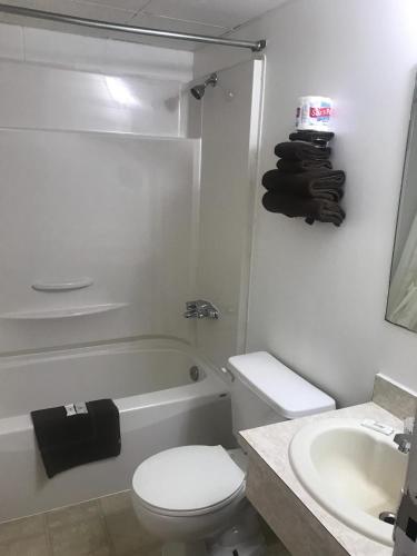 a white bathroom with a toilet and a sink at Raven Motor Inn in High Prairie