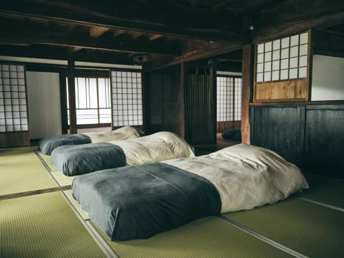 a group of four beds in a room with windows at Kominkayado LOOF Shonoie in Minobu