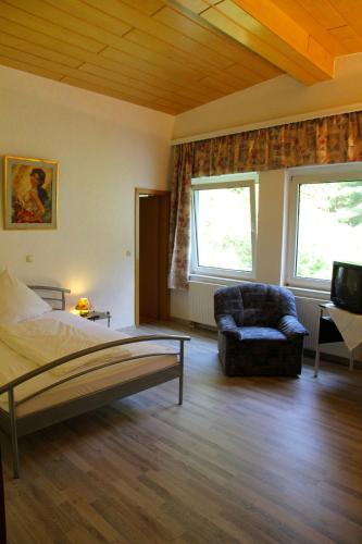 a bedroom with a bed and a chair and a television at Waldhotel Porta Westfalica in Porta Westfalica